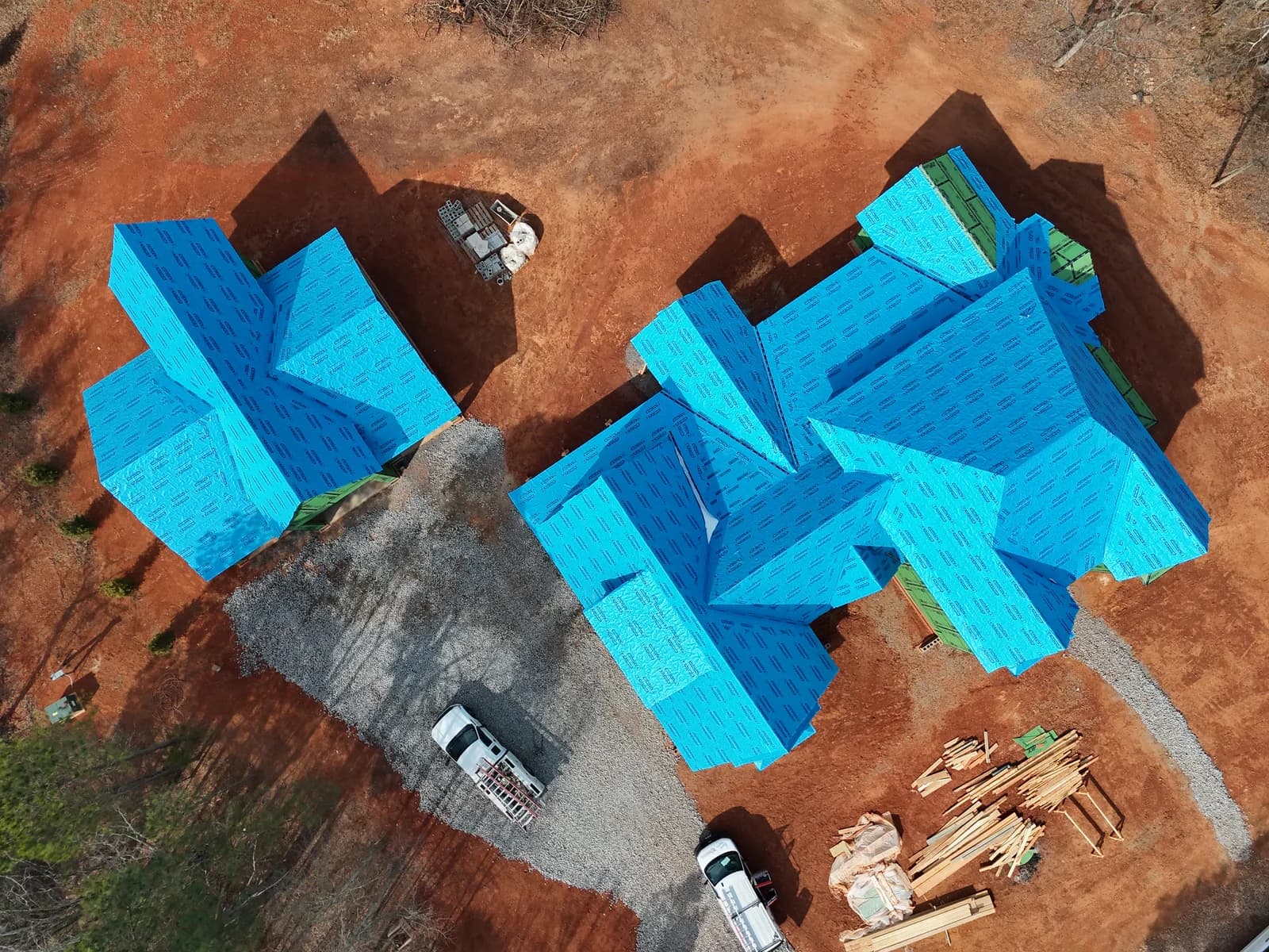 Aerial view of a home under construction with blue roof weather protection